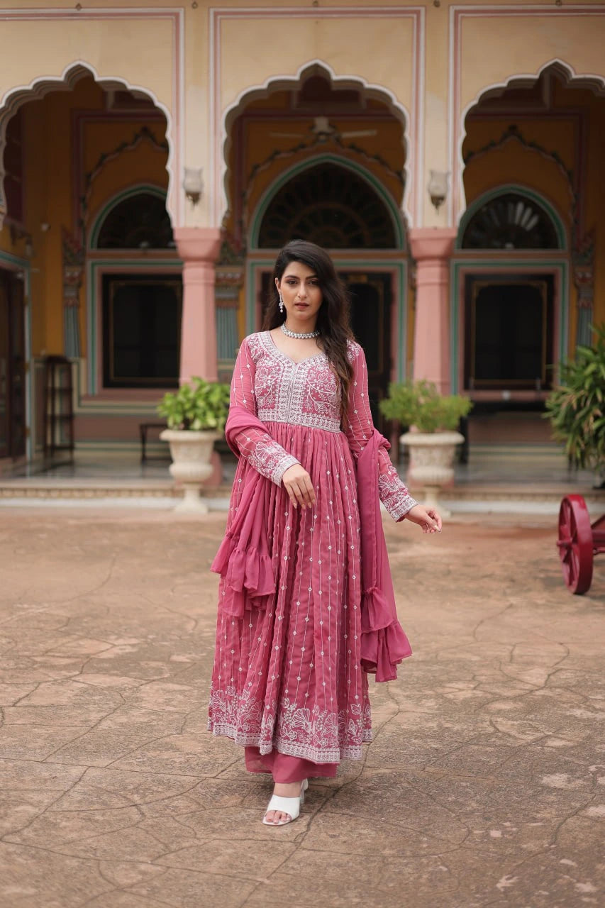 Woman in a pink traditional outfit standing in front of an architectural building.